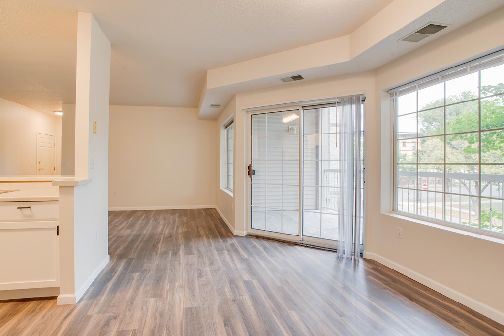 A room with a sliding glass door and wooden flooring.