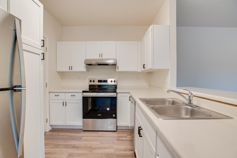 A kitchen with white cabinets and a stainless steel refrigerator.