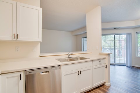 A kitchen with white cabinets and a stainless steel dishwasher.