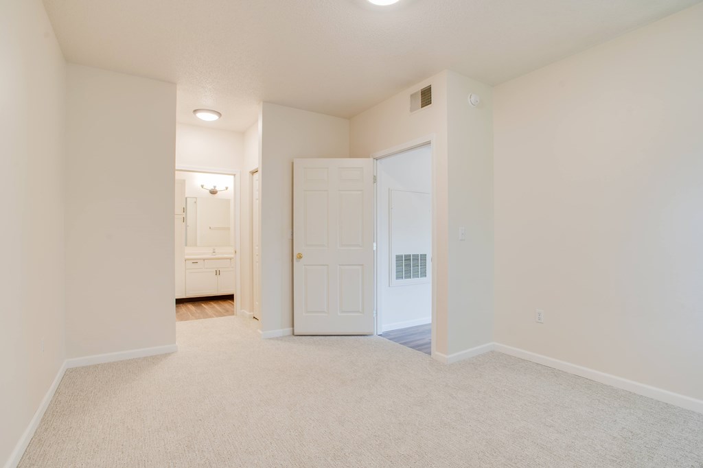 A white room with a carpeted floor and a white door.