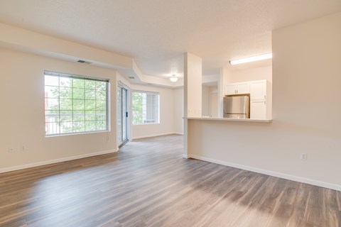 A spacious room with wooden floors and a kitchenette.