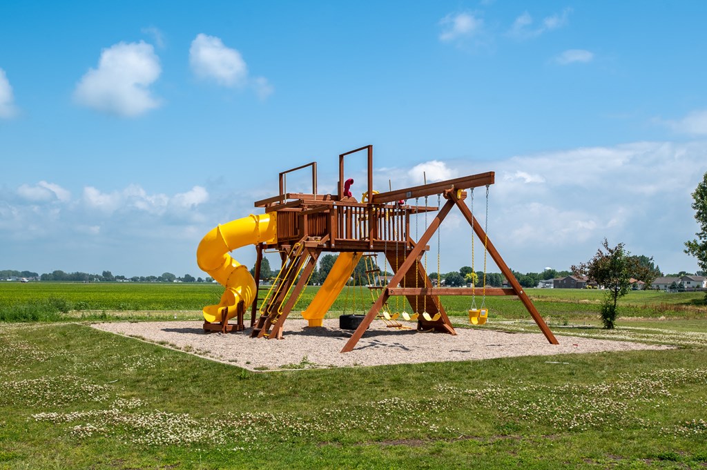 a man sitting on a large yellow swing set in the middle of a grassy field