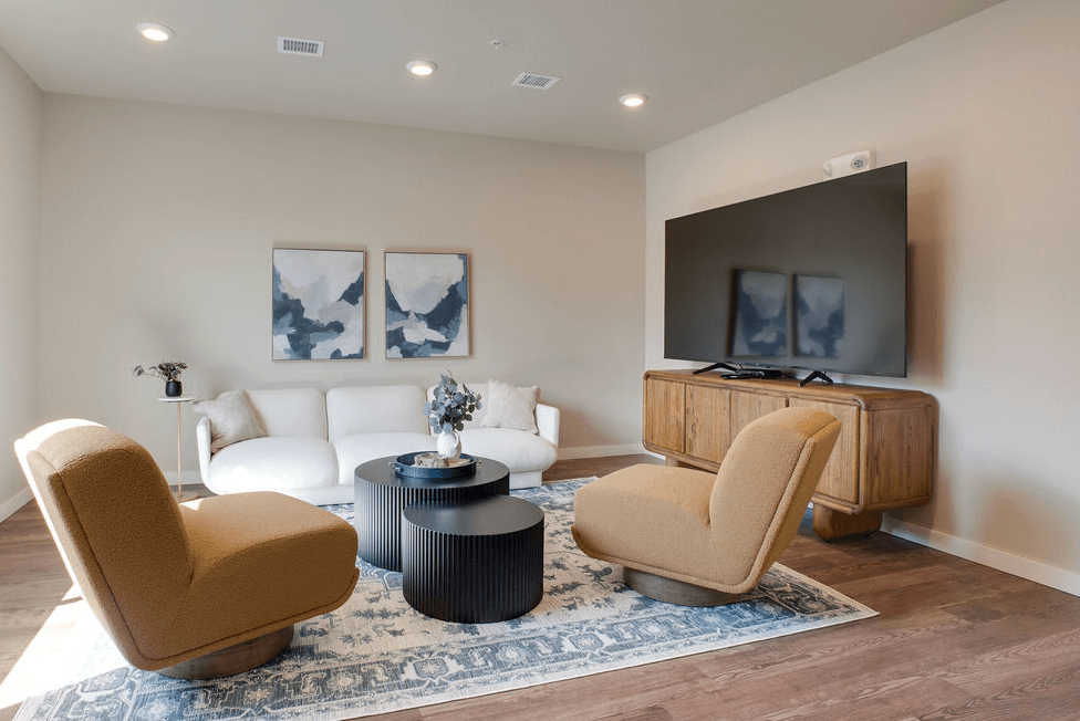 a living room with a white couch and two chairs and a television, Pinehurst Apartments, Baxter