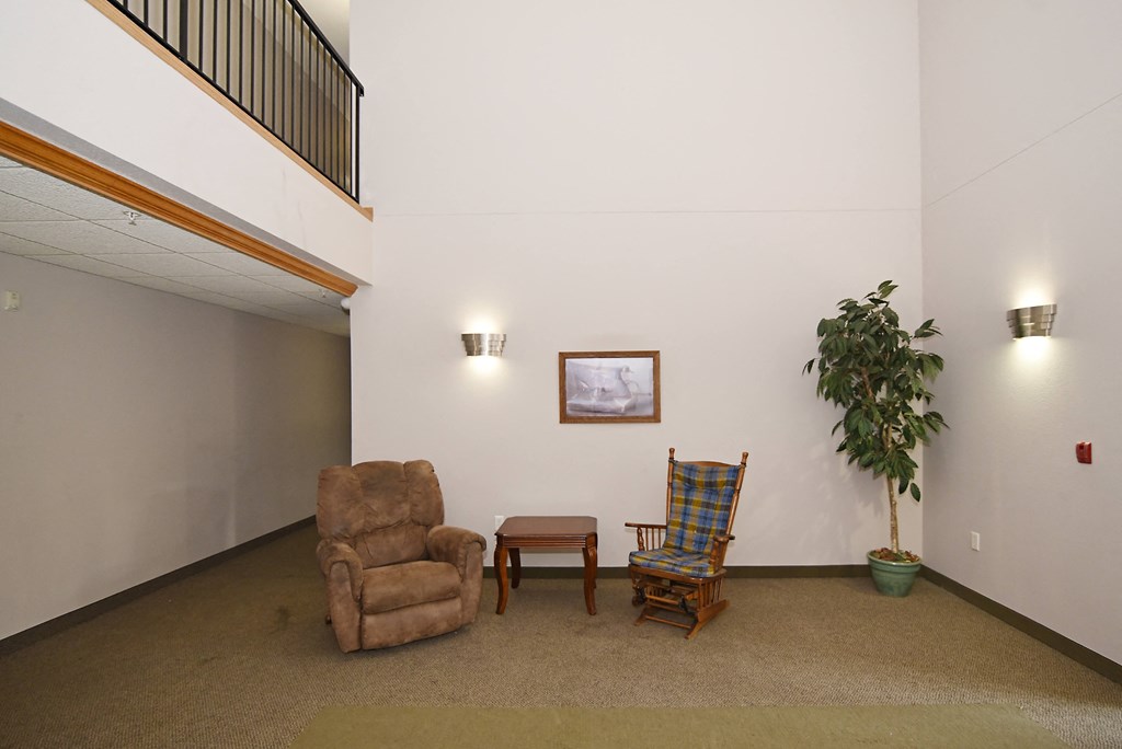 a living room with two chairs and a table and a potted plant