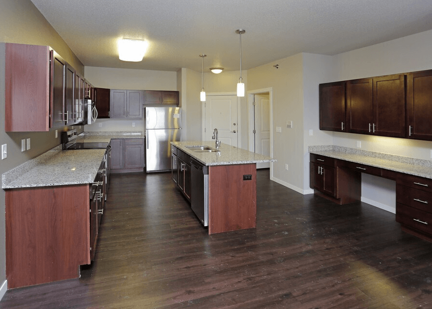 A kitchen with dark wood floors and a marble countertop.