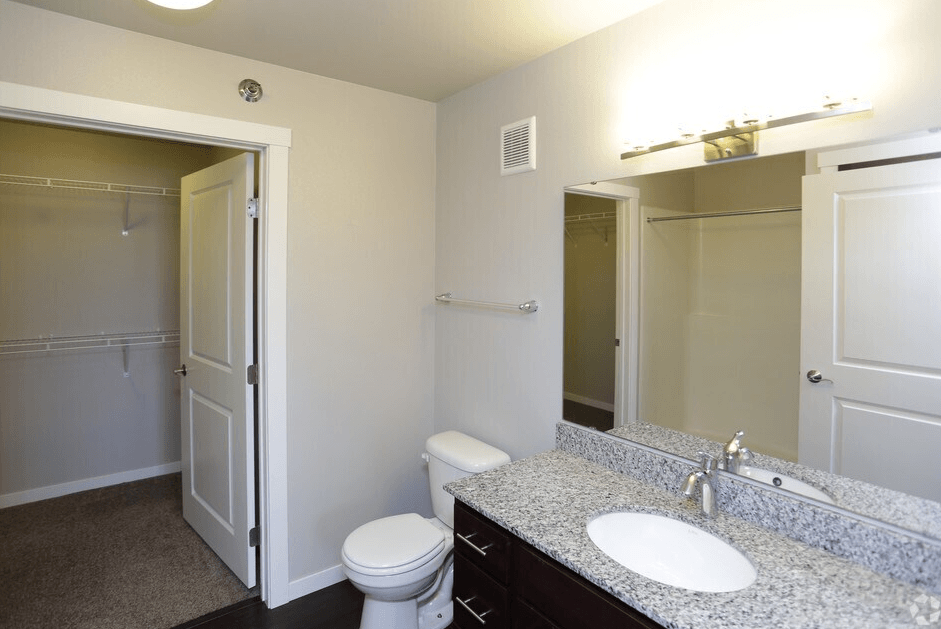 A bathroom with a toilet, sink, and mirror.
