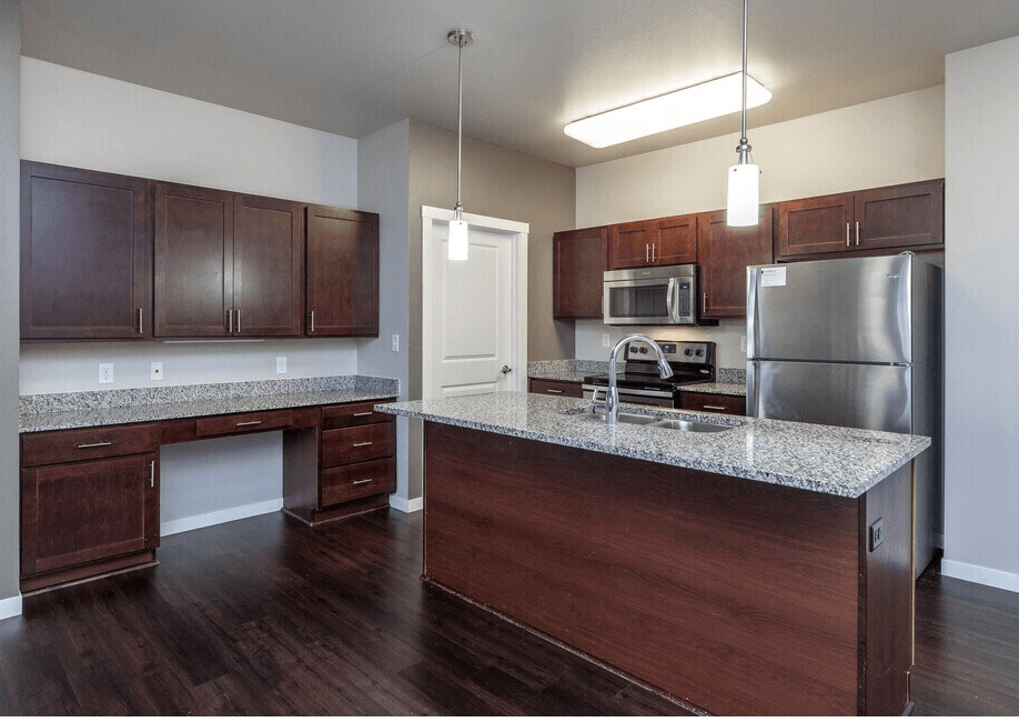 A kitchen with dark wood cabinets and a granite countertop.