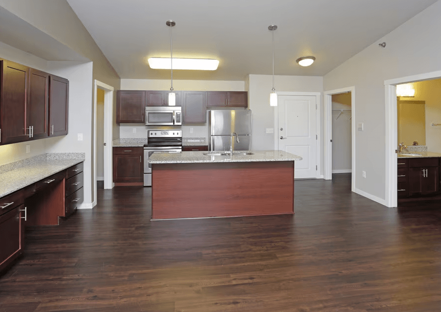 A kitchen with dark wood floors and white walls.