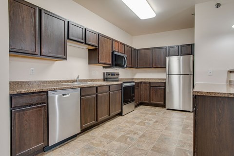 A kitchen with brown cabinets and a stainless steel refrigerator.