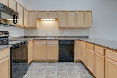A kitchen with wooden cabinets and a black dishwasher.