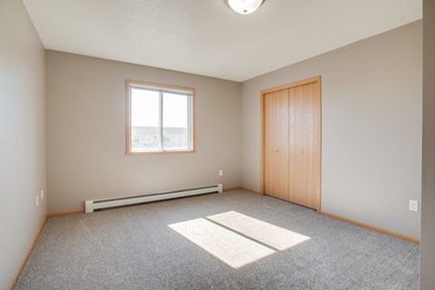 A room with a window, a door, and a carpeted floor.