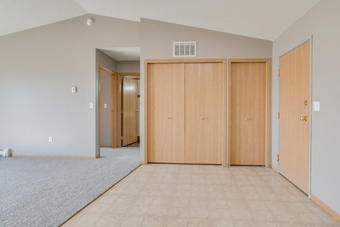 Three wooden doors are closed in a room with a carpeted floor.