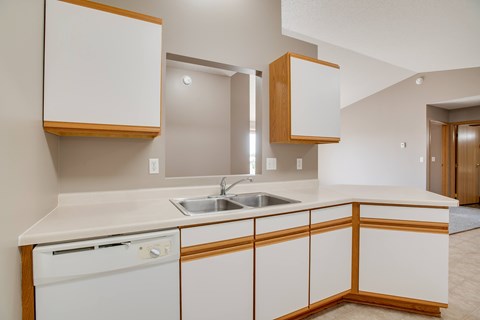 A kitchen with white cabinets and a white dishwasher.