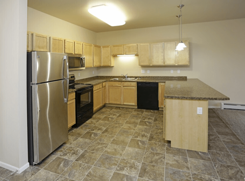 A kitchen with a refrigerator, microwave, oven, and sink.
