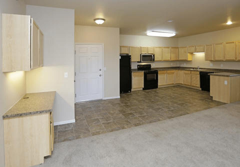 A kitchen with a black refrigerator, microwave, and oven.