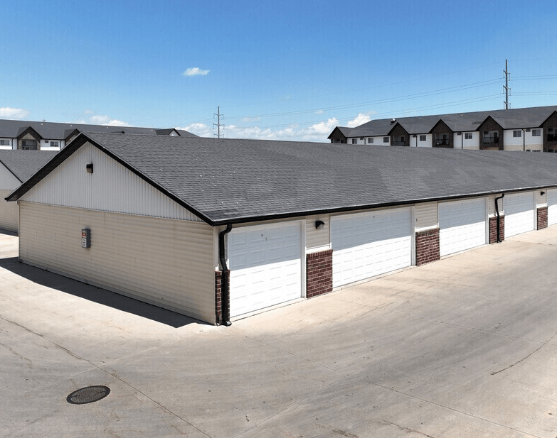 A large garage with a white door is in the foreground with a clear blue sky above. at Shadow Ridge Apartments, West Fargo