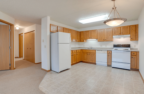 A kitchen with white appliances and wooden cabinets at Savanna  Apartments, St Cloud, MN
