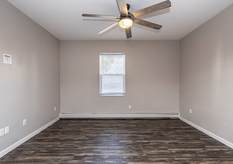 A room with a ceiling fan and wooden flooring.