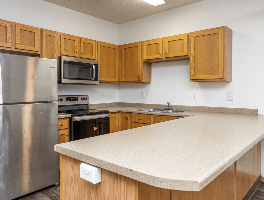 A kitchen with wooden cabinets and a stainless steel refrigerator. at Warehouse Apartments, North Dakota, 58102