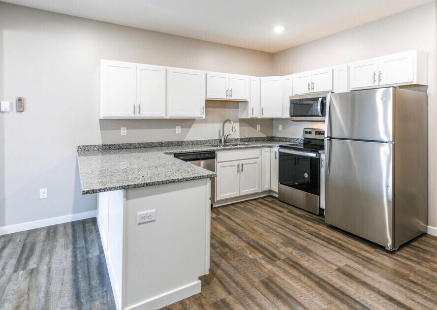 A kitchen with a granite countertop and stainless steel appliances. at Warehouse Apartments, North Dakota