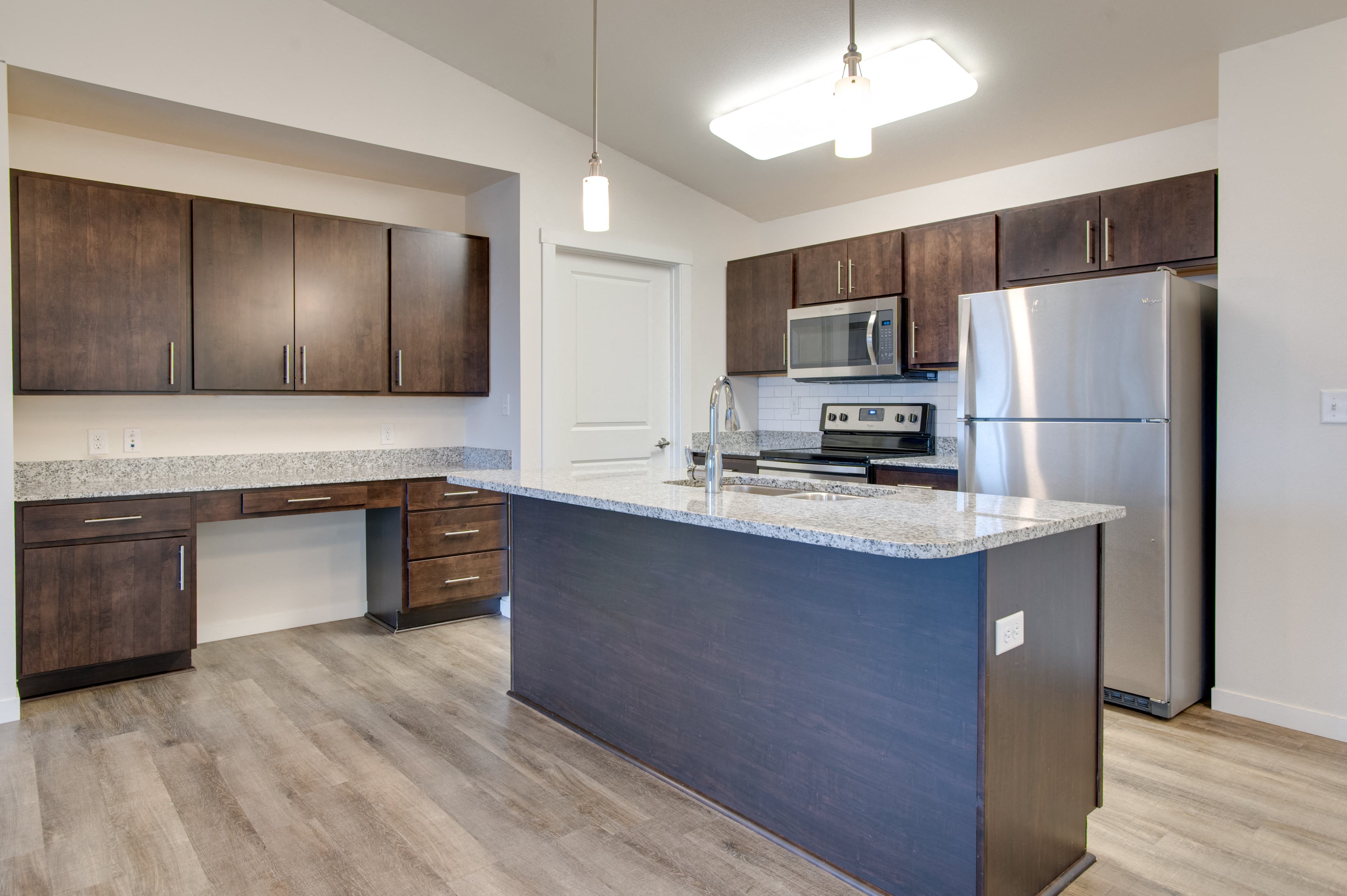 a kitchen with a large island and stainless steel refrigerator