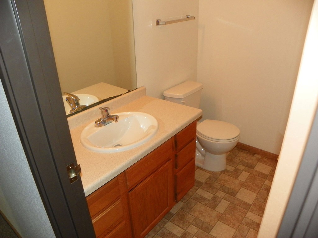 A bathroom with a toilet, sink, and tiled floor.