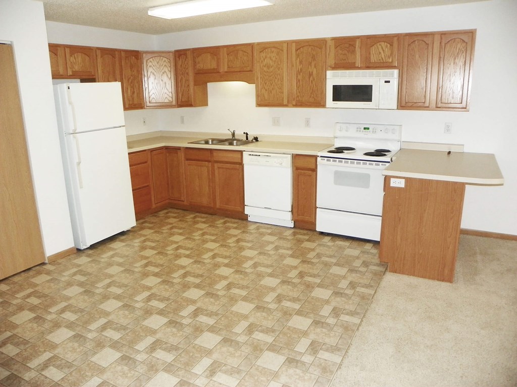 A kitchen with white appliances and wooden cabinets.