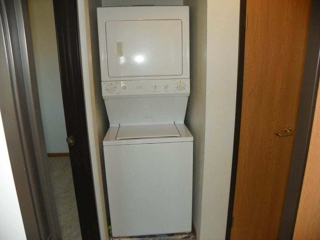 A small white washing machine sits in a narrow hallway.