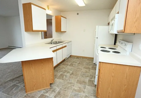 A kitchen with white appliances and wooden cabinets.