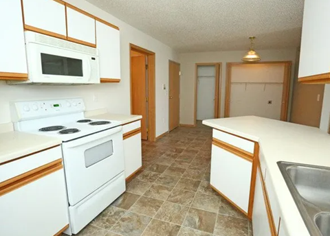 Kitchen with white appliances and ample counter space at Bella Place Apartments, West Fargo