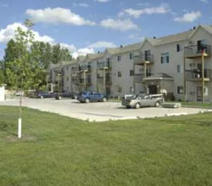 Apartment building with cars parked in front.