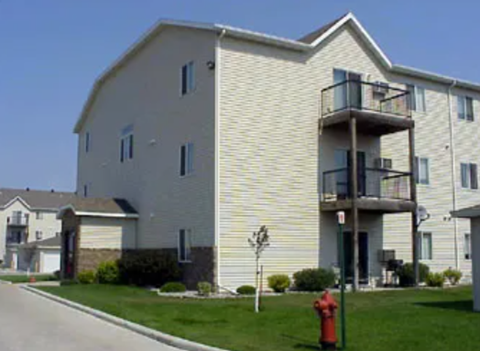 A fire hydrant is in front of a two-story apartment building.