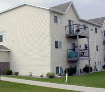 A white two story apartment building with a balcony on the second floor.