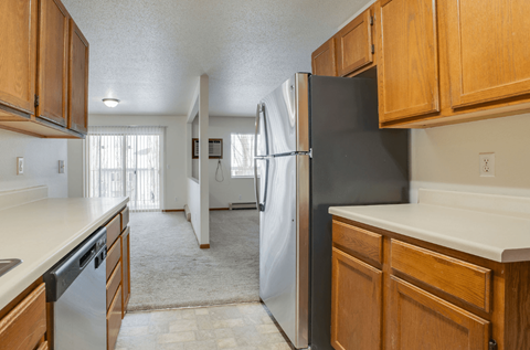A kitchen with a black refrigerator and wooden cabinets.