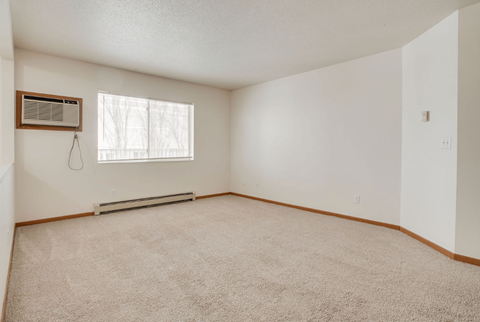A room with a carpeted floor and a window with blinds.