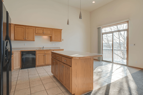 A kitchen with wooden cabinets and a black refrigerator.
