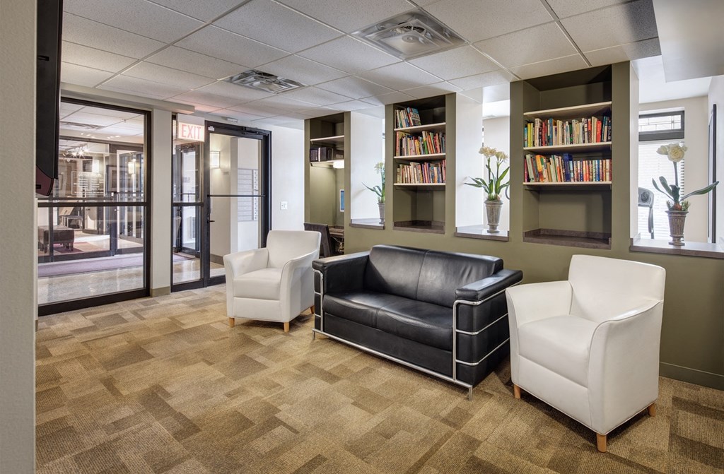 a lounge area with leather couches and chairs and a book shelf