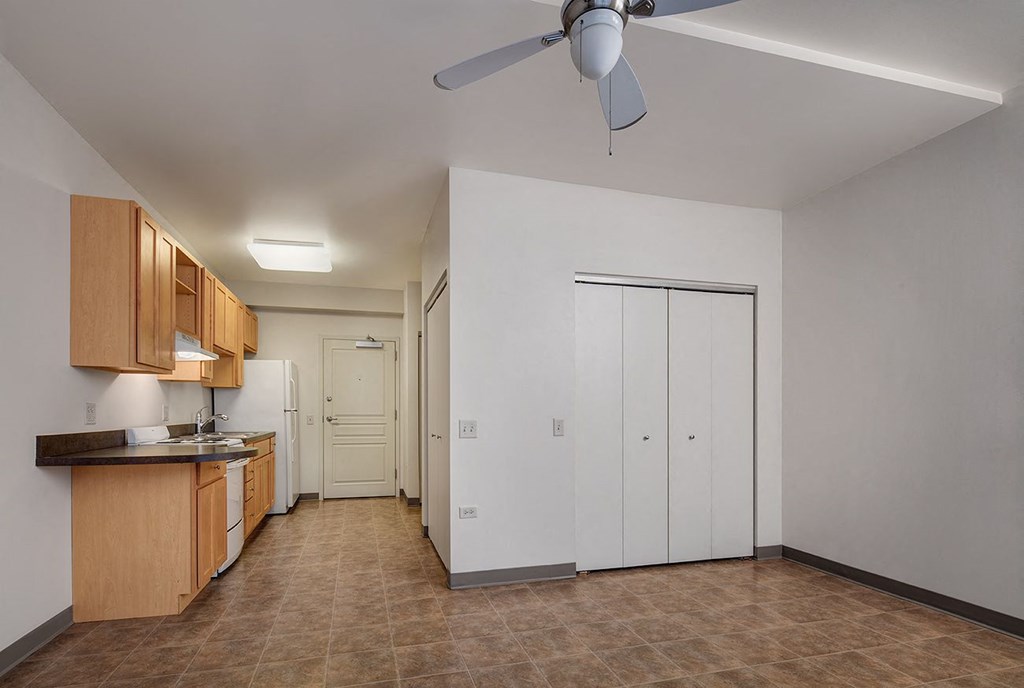 a room with a kitchen and a ceiling fan