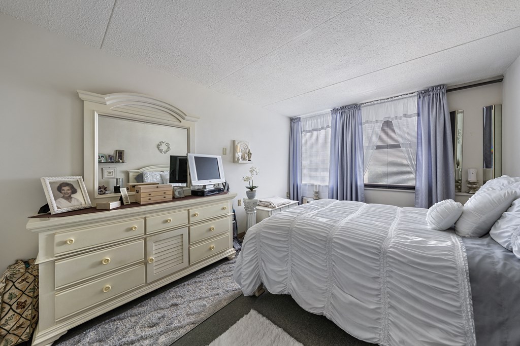a bedroom with a large bed and a dresser with a mirror