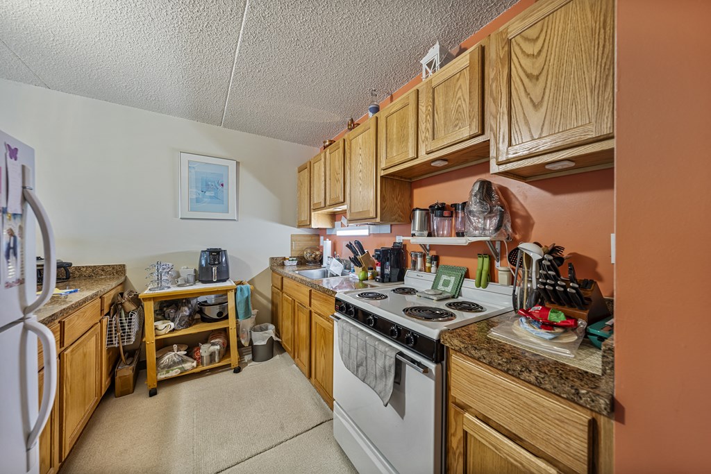 a kitchen with wood cabinets and white appliances and a stove top oven