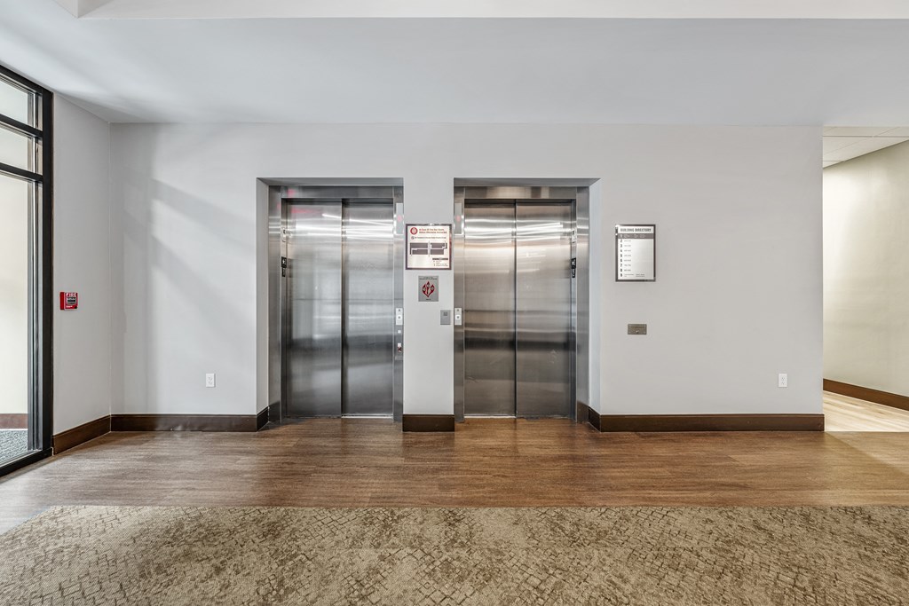 a lobby with elevators and a rug in front of the elevator doors