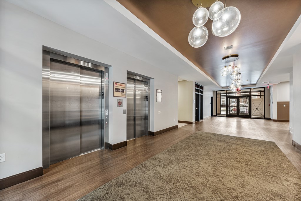 a lobby with elevators and a carpeted floor and stainless steel doors