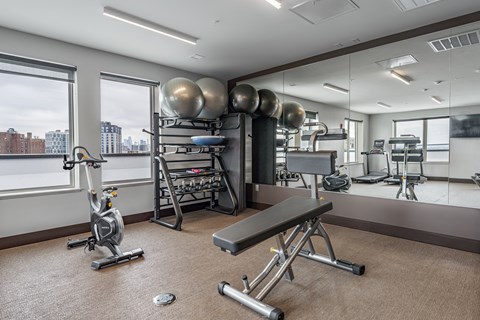 a fitness room with weights and exercise equipment and large windows