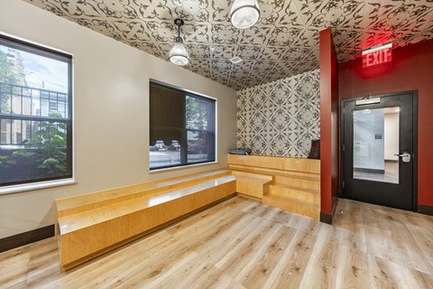 a waiting room with a wooden bench and a red door