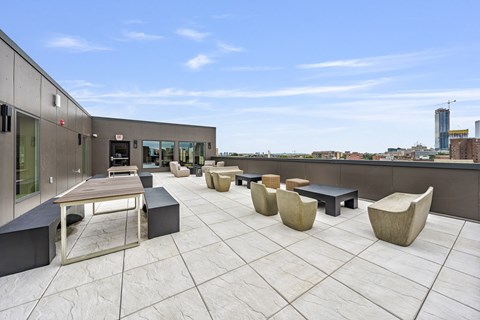 a rooftop patio with tables and benches and a view of the city
