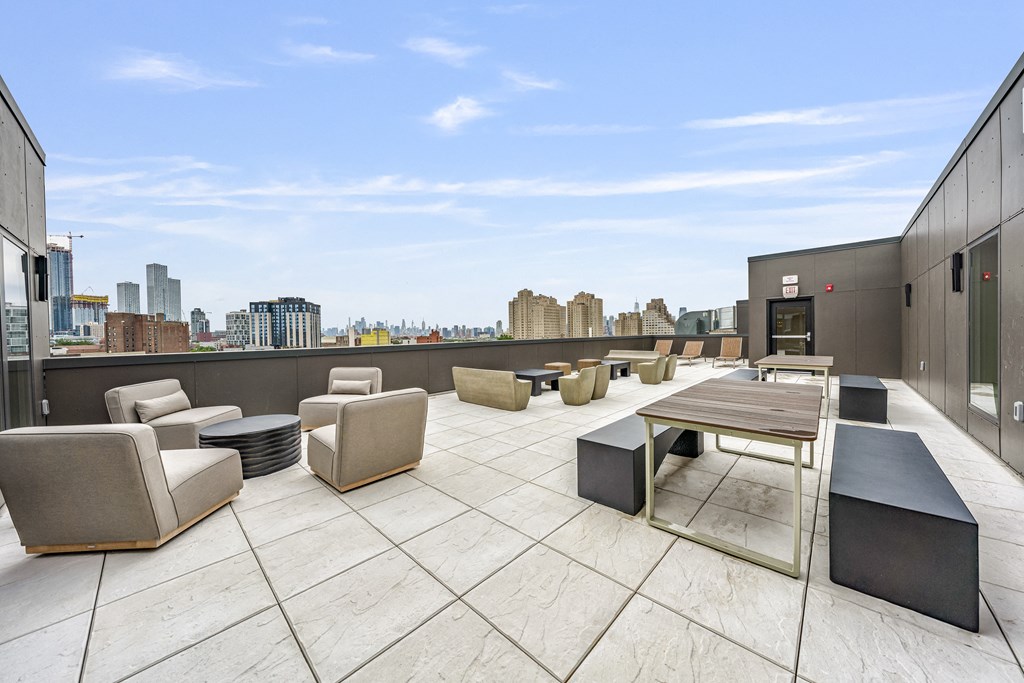 a rooftop patio with chairs and tables and a view of the city
