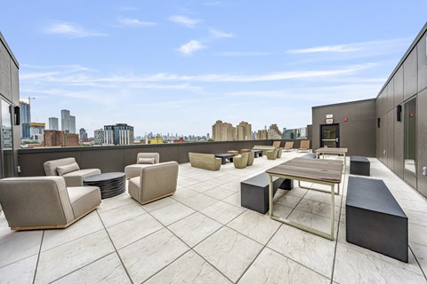 a rooftop patio with chairs and tables and a view of the city