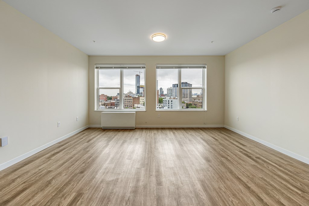 an empty living room with three windows and wood flooring