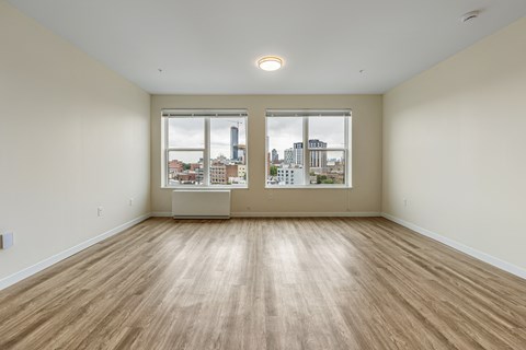 an empty living room with three windows and wood flooring