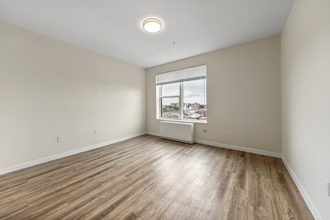 an empty living room with wood floors and a window